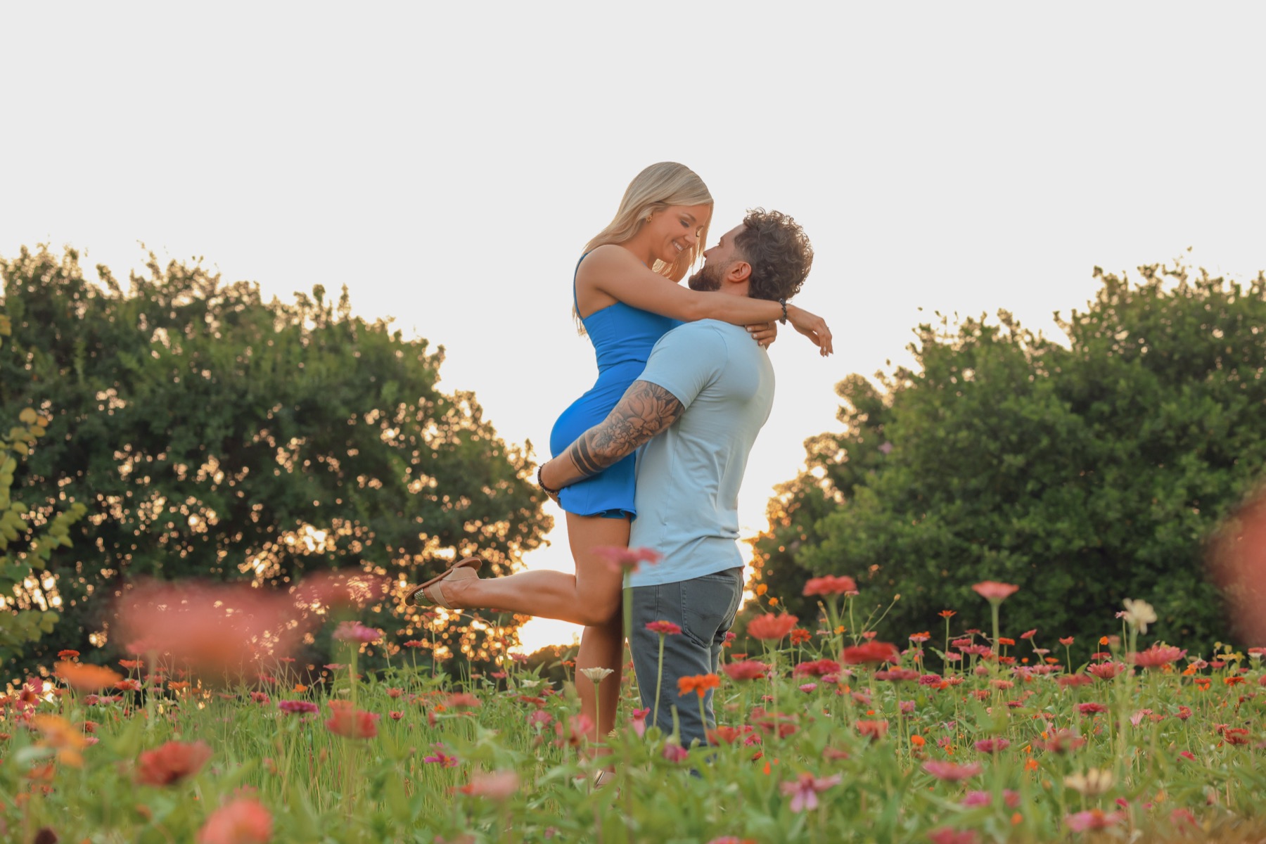 Phil lifting Sarah in a field of wildflowers.
